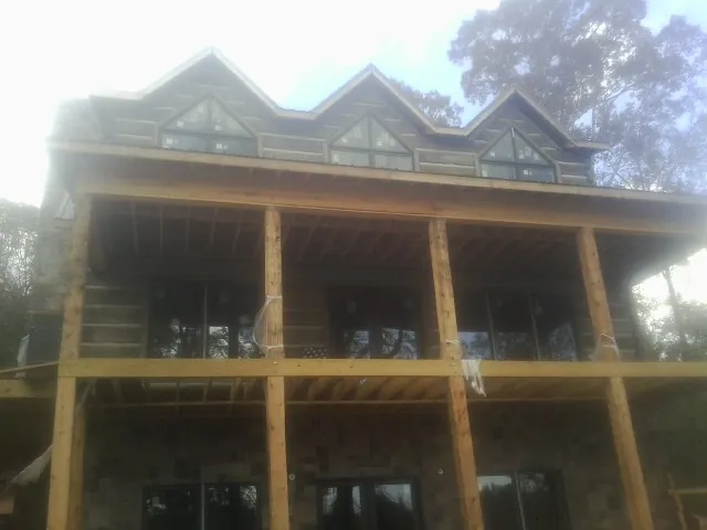 Dormers and porch framing on a large log home under construction — Roof Coating work by our crew in Hesston