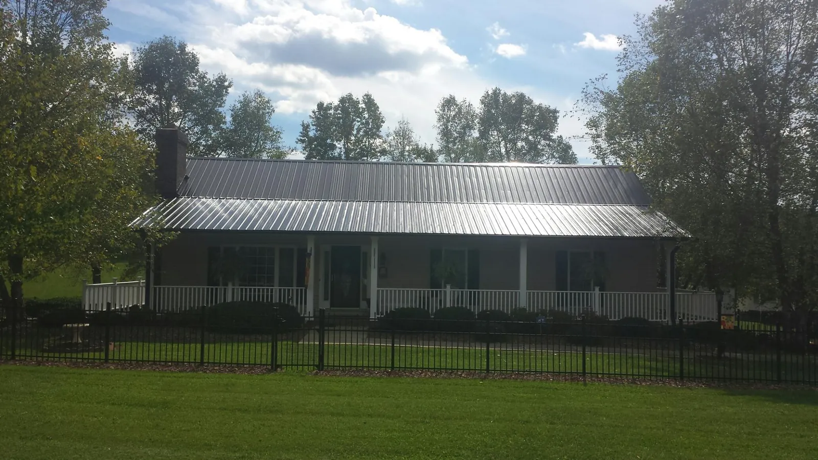Gray metal roof on a brick ranch with a full width front porch — Gutter Guard Installation work by our crew in Hesston