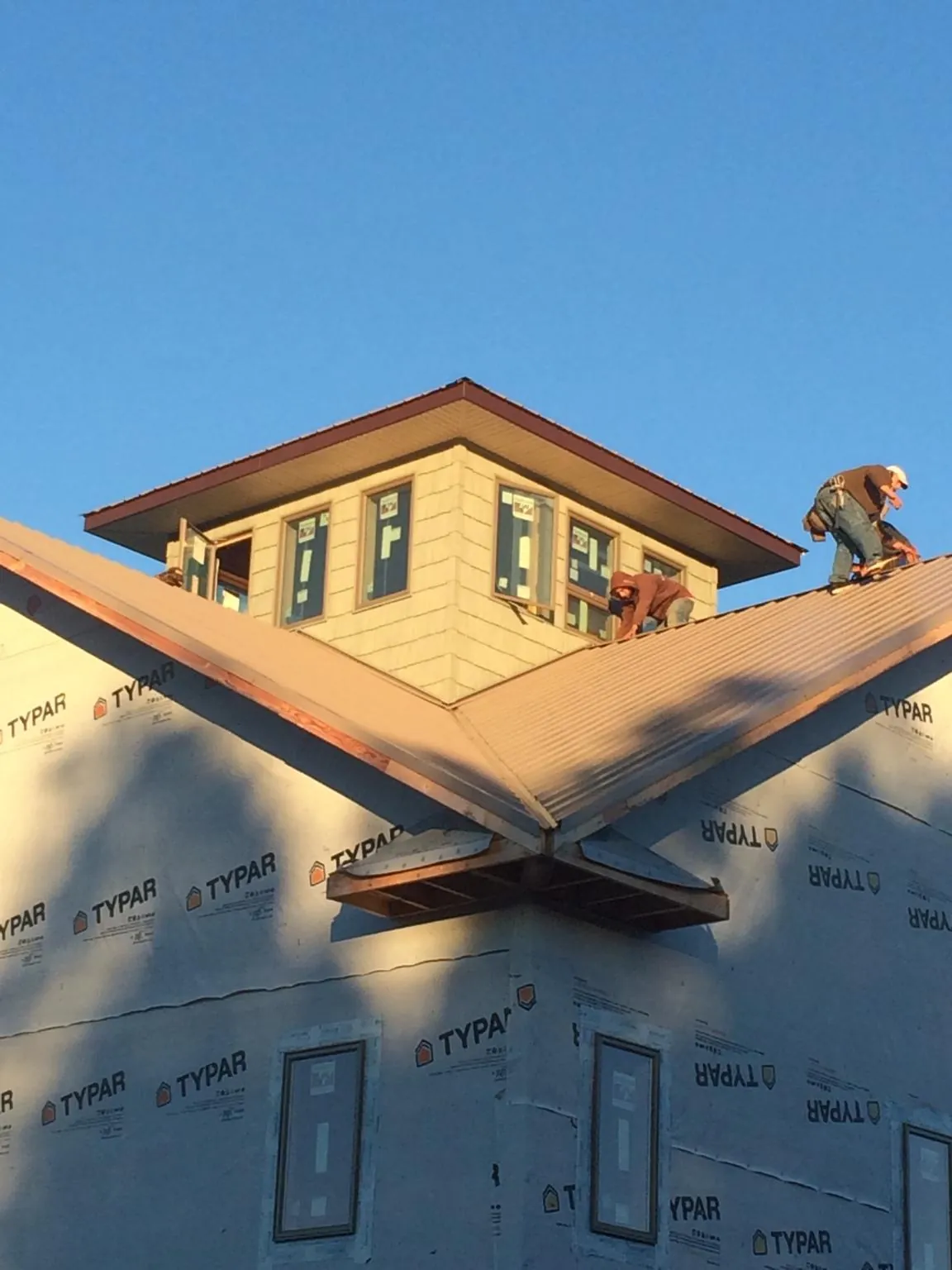 Roofers working around a rooftop cupola on a new metal roof at sunset — Roof Waterproofing in Hesston by Roofing Brothers